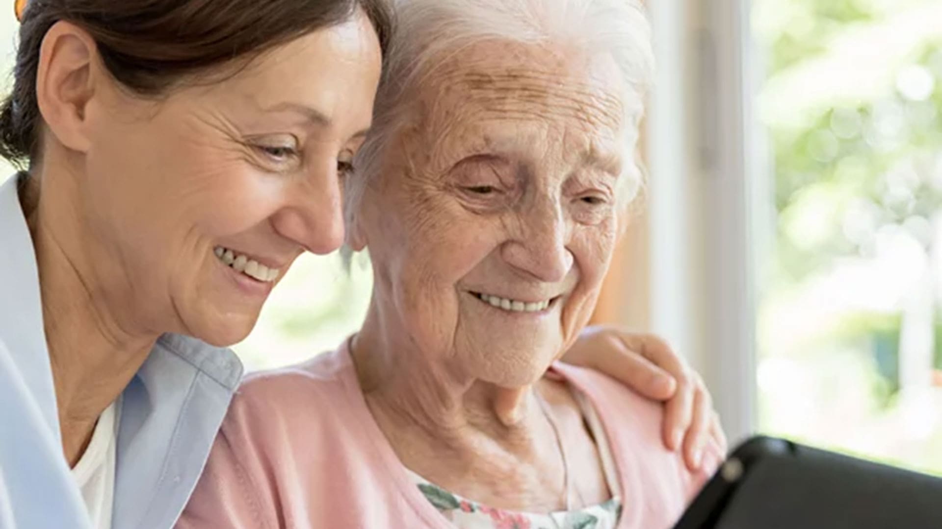 senior mom and daughter looking at a tablet